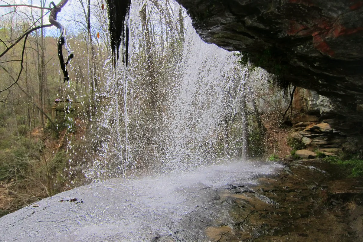Issaqueena Falls spilling over a rock ledge near Walhalla in Oconee County, South Carolina, seen from beneath the overhang
