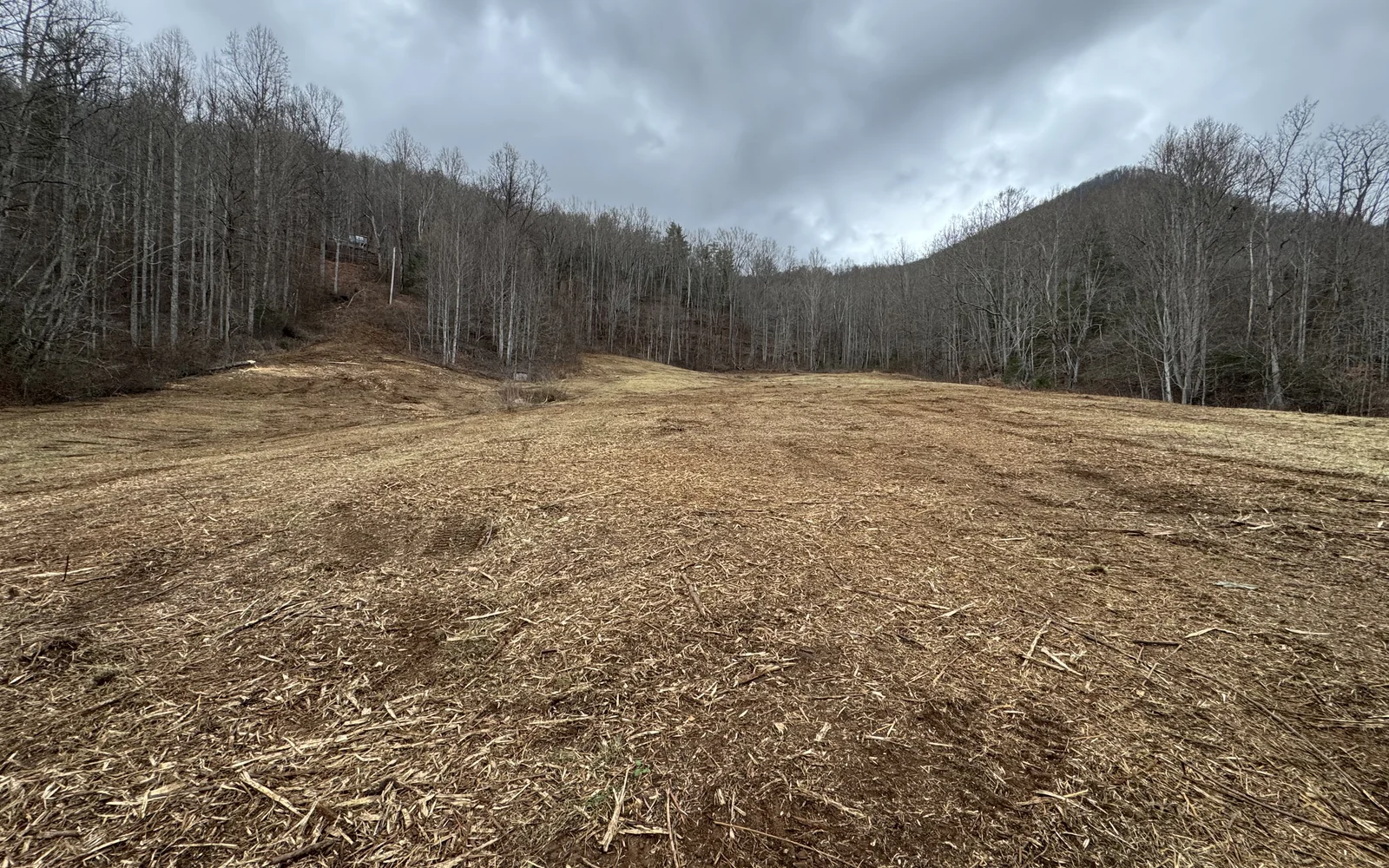 Freshly cleared acreage between wooded mountain slopes